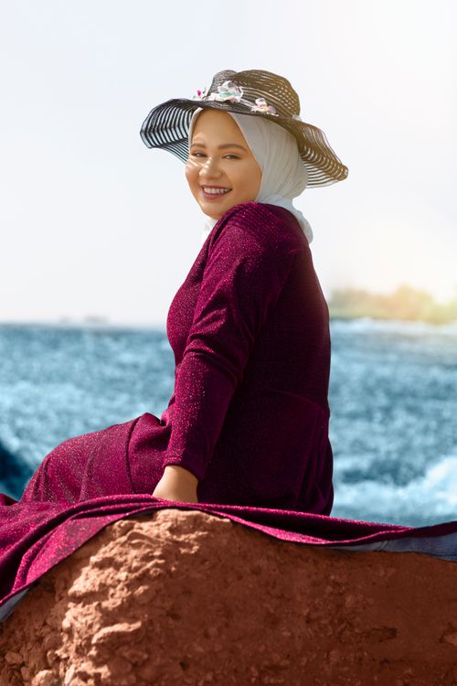 Free A young woman enjoys a sunny day by the sea, showcasing elegance and joy. Stock Photo