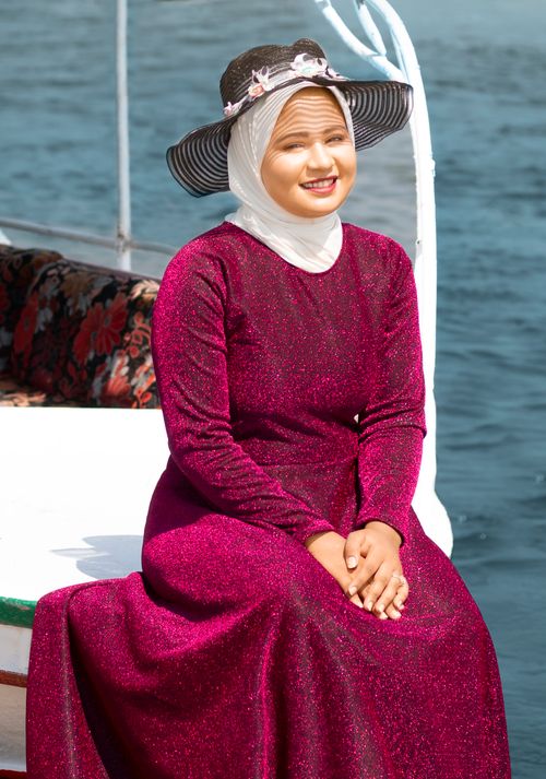 Free A young woman in a sparkling outfit and hat enjoys a sunny day by the sea. Stock Photo