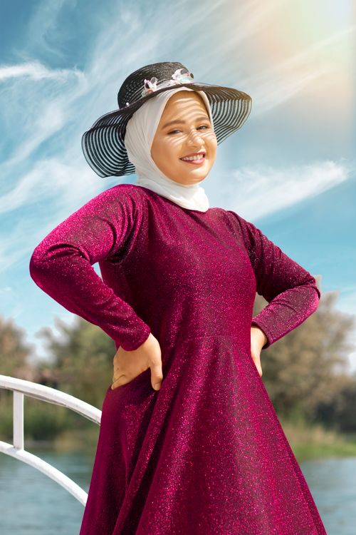 Free A fashionable woman in a sparkly dress and hat enjoying a sunny day outdoors. Stock Photo