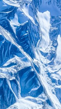 Stunning aerial view capturing the rugged beauty of snow-covered mountain peaks in winter.