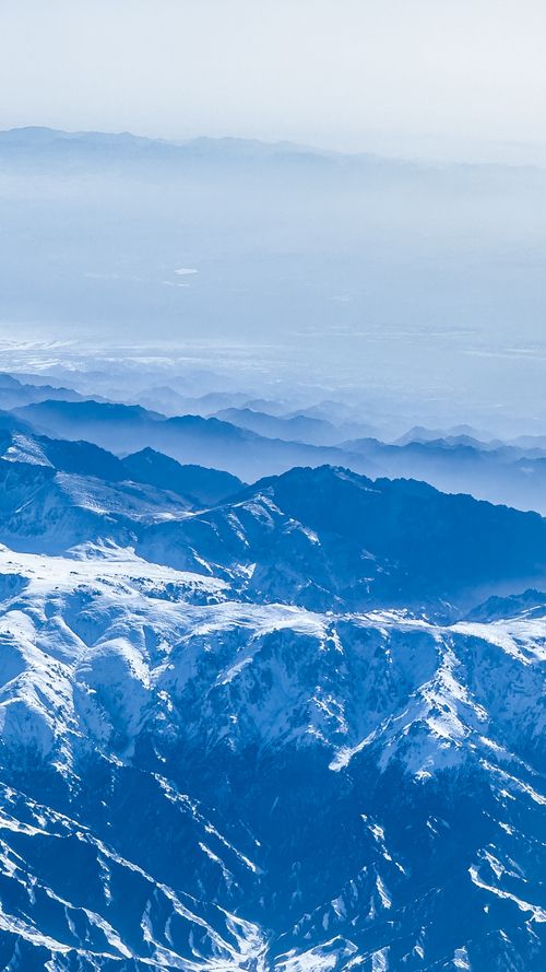 Free A breathtaking aerial view of snow-capped mountains surrounded by mist and fog. Stock Photo