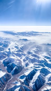 Stunning aerial shot of a snow-covered mountain range under a bright winter sky.