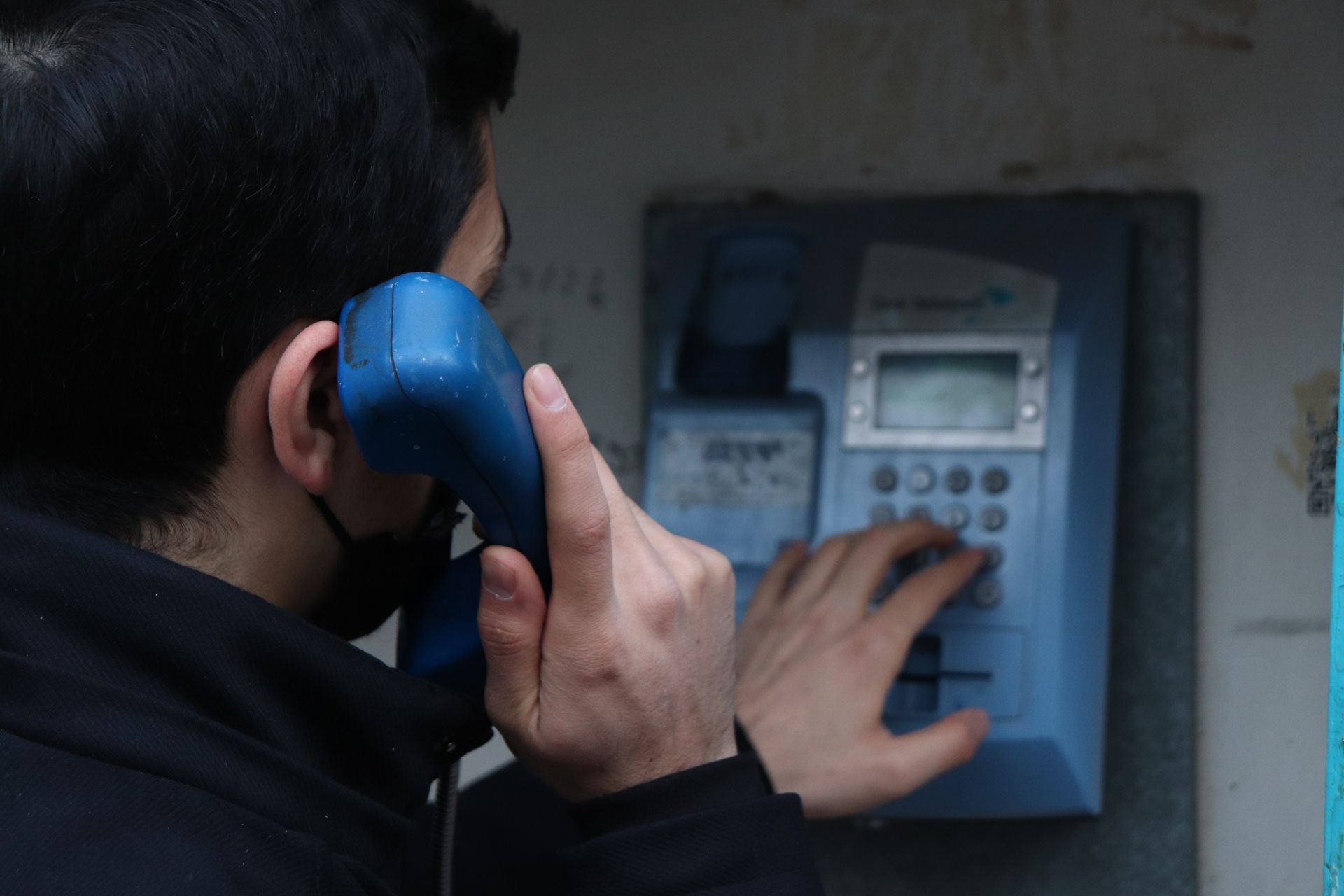 Close-up of a man using a public telephone in Malatya, Türkiye.