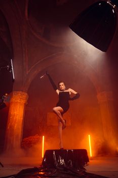 Elegant fashion model posing in a dramatic studio setting with vintage vibes.