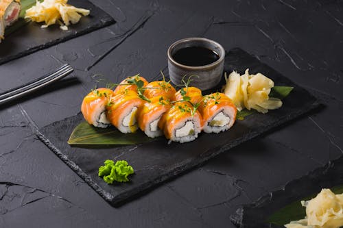 Free A delectable salmon sushi roll served with soy sauce, wasabi, and pickled ginger on a stone platter. Stock Photo