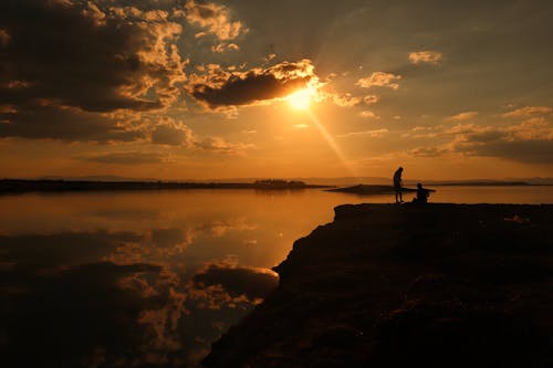 Silhouette of People Standing on the Cliff During Golden Hour 