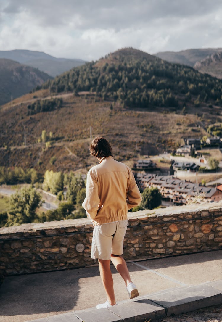 Man Walking Near Wall With Hills Behind