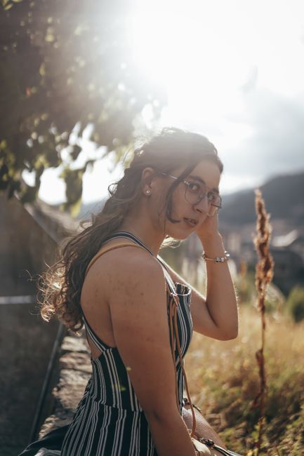 Chic portrait of a young woman in glasses enjoying a sunny day outdoors, embodying fashion and style.