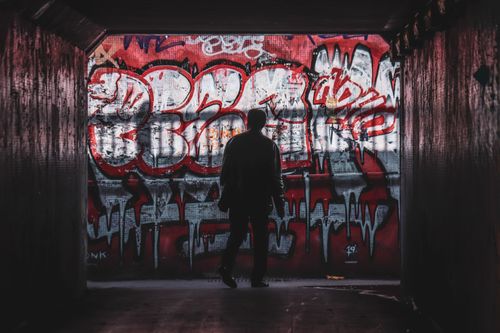 Free A person silhouetted against colorful graffiti art in a Bristol tunnel. Stock Photo