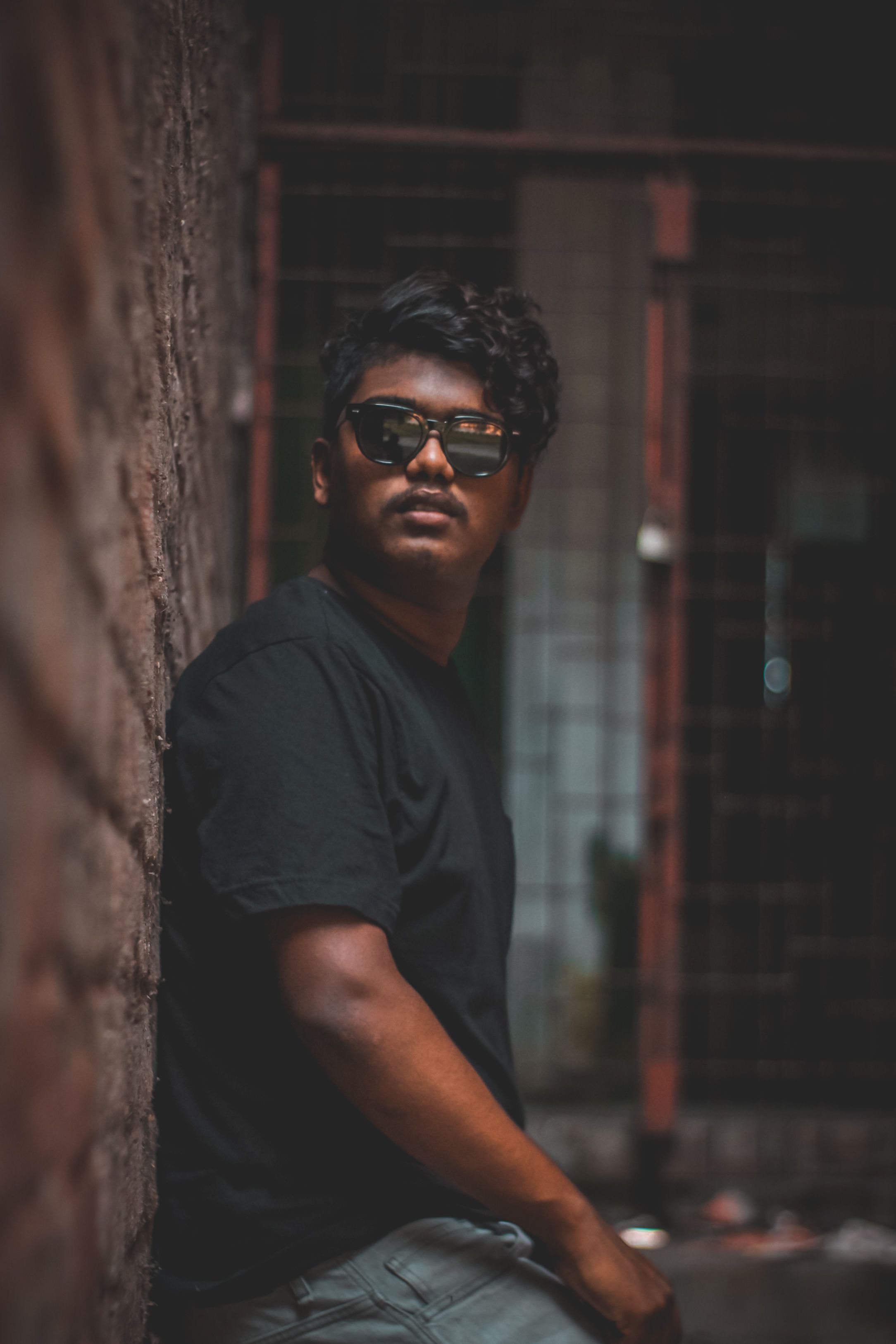 A Man in Black Shirt Wearing Sunglasses while Leaning on the Wall ...