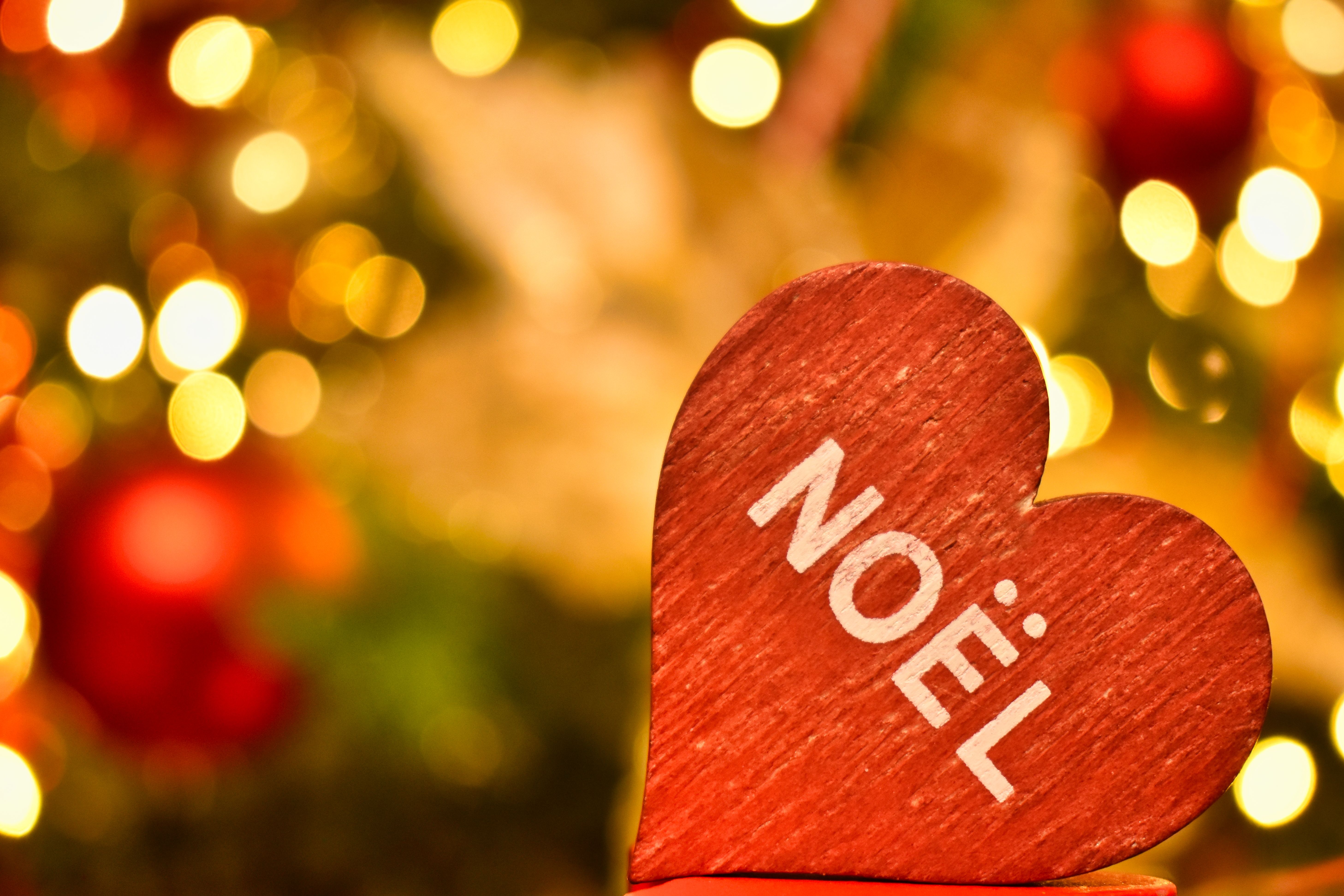 A wooden heart with 'Noël' text framed by Christmas lights, evoking festive warmth.