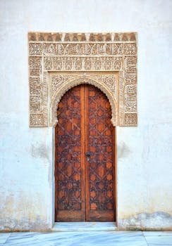 Elegant Moorish wooden door set in a detailed stone arch in Granada, Spain.