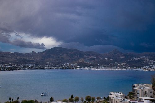 Free Dramatic storm clouds loom over Yalıkavak Bay, showcasing the serene yet captivating coastline of Muğla, Türkiye. Stock Photo