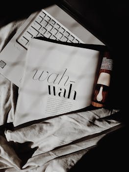 Stylish minimal setup featuring a laptop and magazine on white fabric.