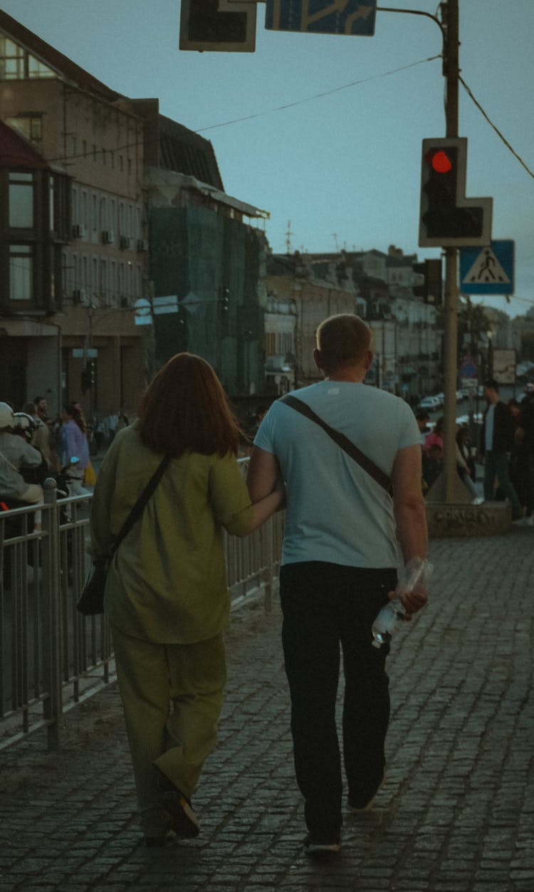 A Back View Of A Couple Walking On The Street Together