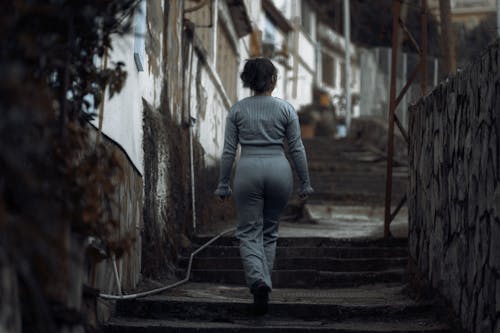 Woman in Gray Sweatshirt Walking Up the Staircase