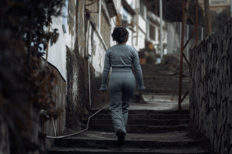 Woman In Gray Sweatshirt Walking Up The Staircase