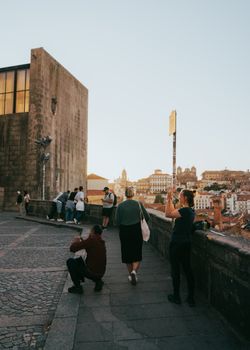 Tourists capturing scenic views of Porto, Portugal, at sunset.