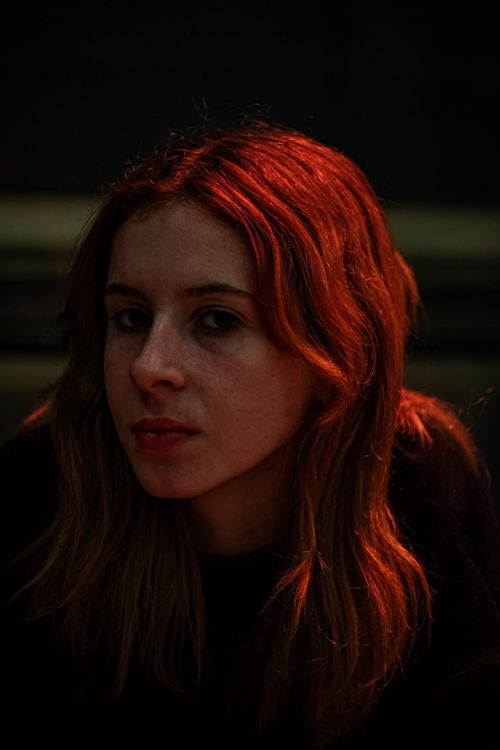 Free A captivating portrait of a woman with red hair illuminated artfully. Stock Photo
