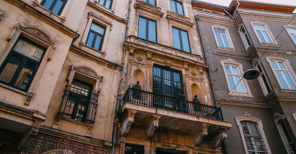 Upward view of classic European building facades with decorative elements and balconies.