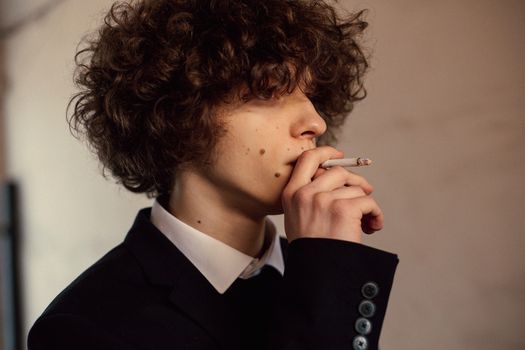 Side profile of a young man in a suit smoking, captured in intimate focus.