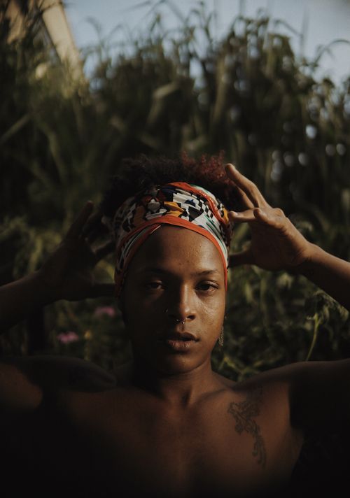 Free A striking portrait of a woman wearing a colorful headscarf in a natural outdoor setting. Stock Photo