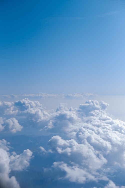 Free Peaceful aerial view of fluffy cumulus clouds against a bright blue sky, capturing nature's tranquility. Stock Photo