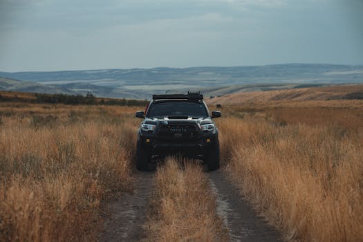 A Toyota pickup truck navigating an unpaved road in a vast grassland, ideal for off-road adventures.