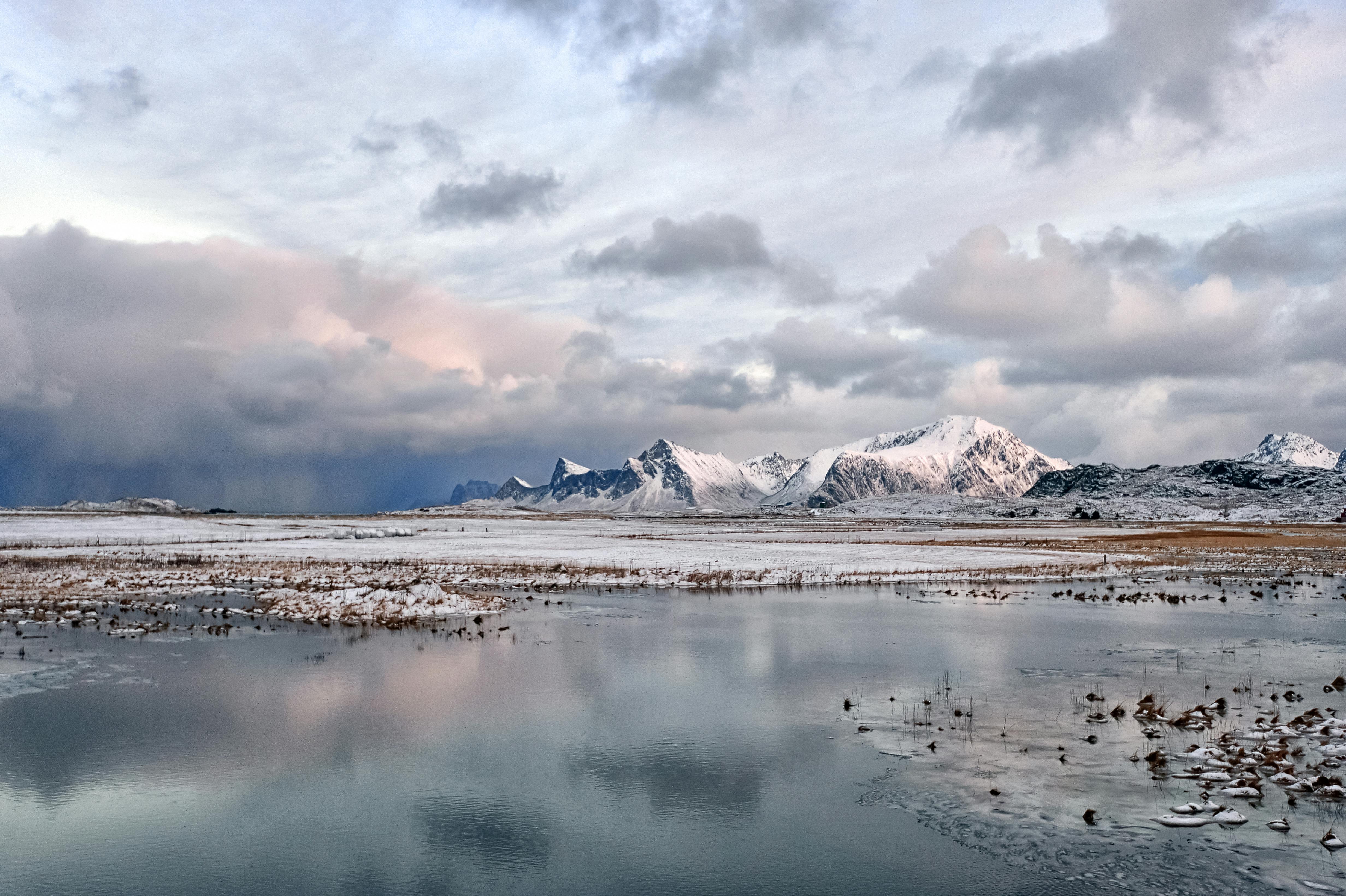 Majestic snowy mountains and calm lake in Fredvang, Norway with stunning winter scenery.