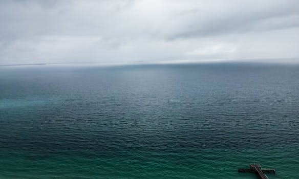 Expansive aerial view of the blue ocean meeting the cloudy sky at Coogee Beach, Western Australia.