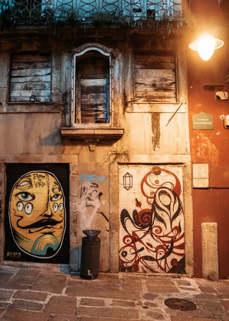 Intricate graffiti on a historic building wall in Portas, Portugal, at night.