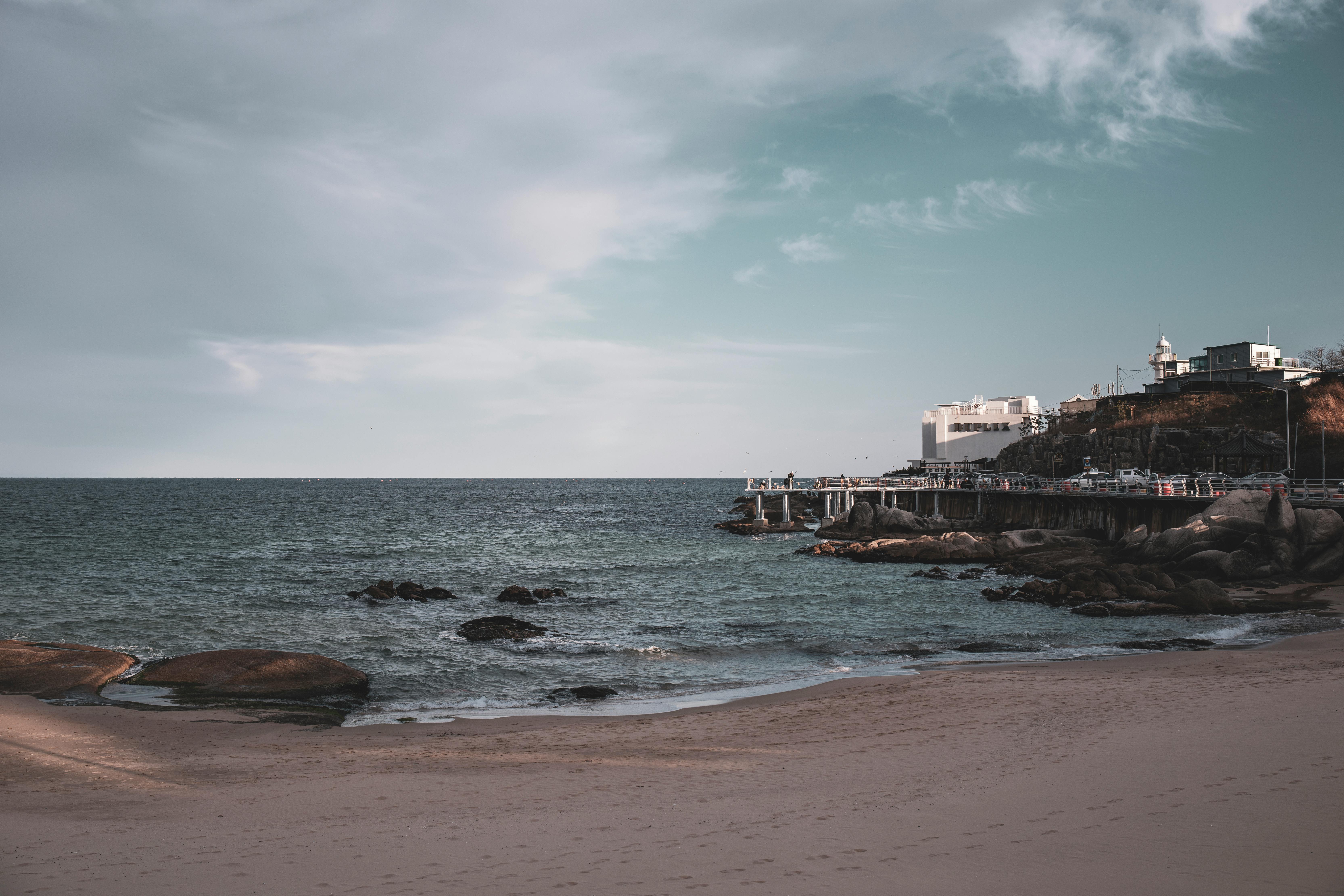 Beautiful seascape with sandy beach, promenade, and distant buildings in Goseong, South Korea.