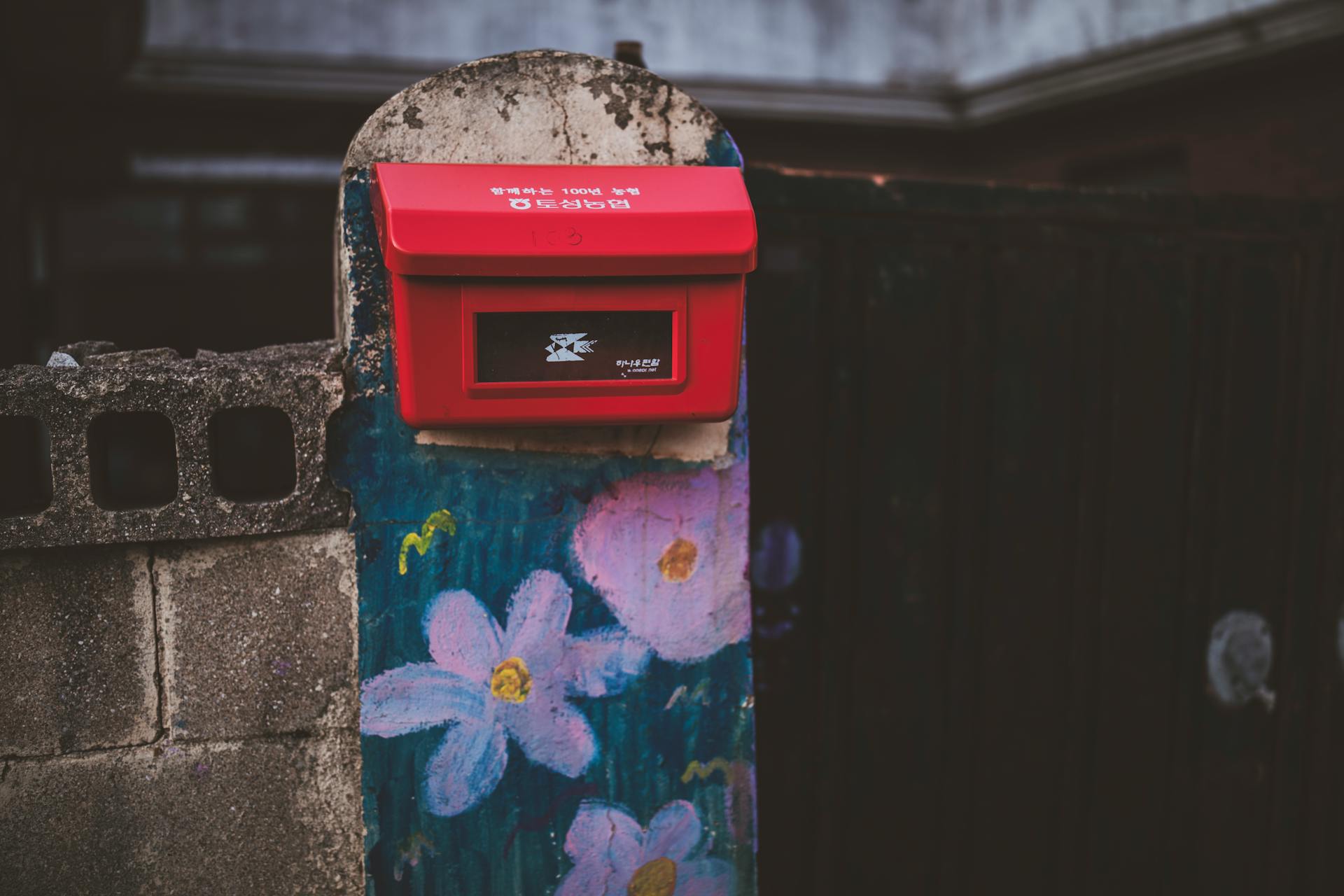 Vibrant red mailbox mounted on colorfully painted stone wall in Goseong-gun, South Korea.