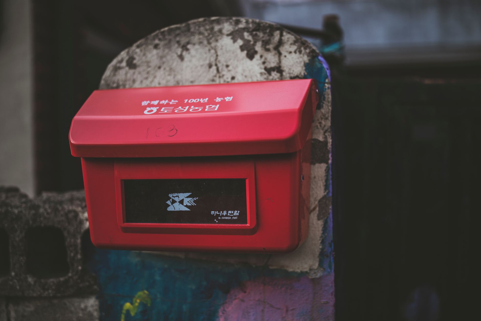 Close-up of a red metal mailbox mounted on a concrete post in Goseong-gun, South Korea.