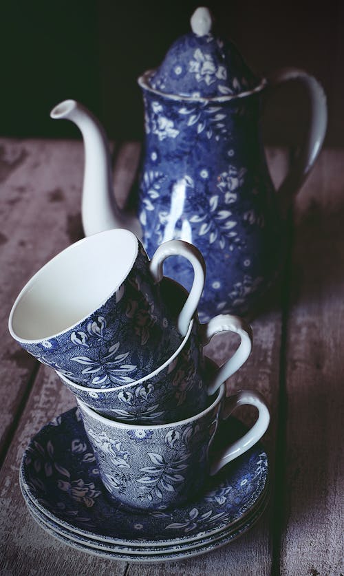 Blue and White Floral Ceramic Teacup and Teapot on Brown Wooden Table