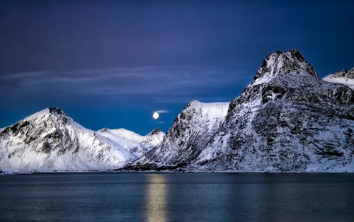 Free Stunning view of snowy mountains under a moonlit sky in Lofoten, Norway. Stock Photo