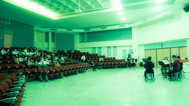 Musicians performing in a spacious auditorium with a small audience seated.