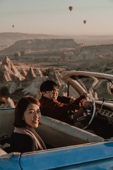 Two people enjoying a drive in a convertible with a scenic view.
