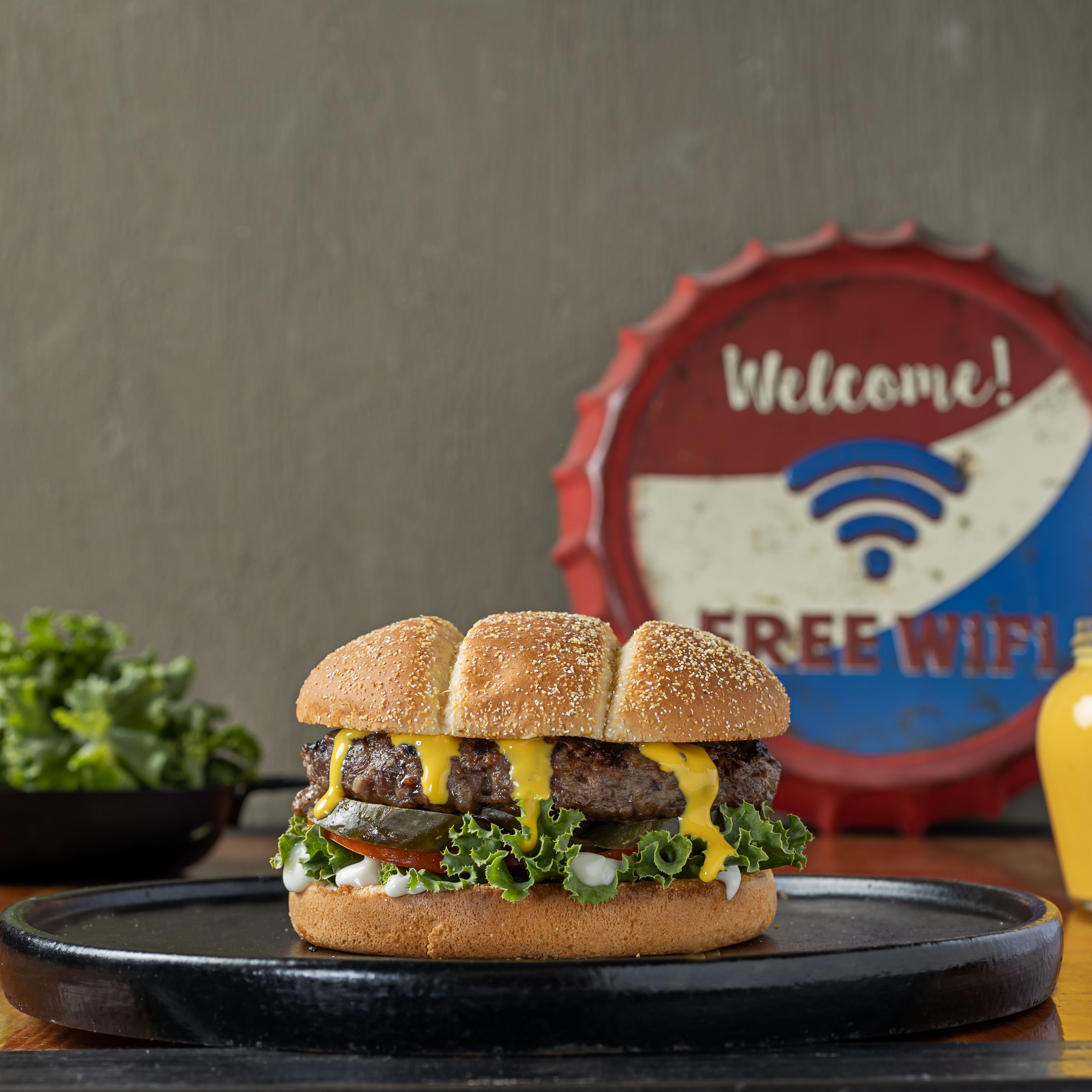 Delicious burger with melted cheese and fresh toppings on a rustic platter.