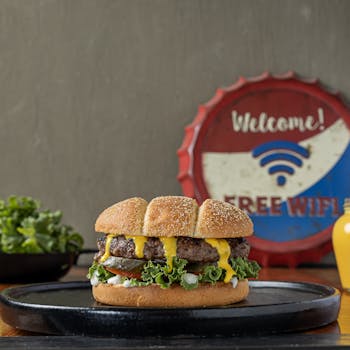 Delicious burger with melted cheese and fresh toppings on a rustic platter.