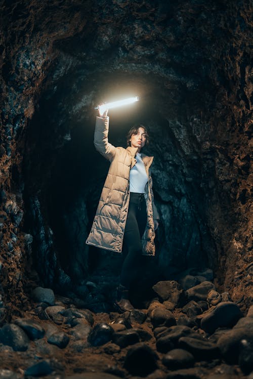 A Woman in Beige Jacket Standing Inside the Cave
