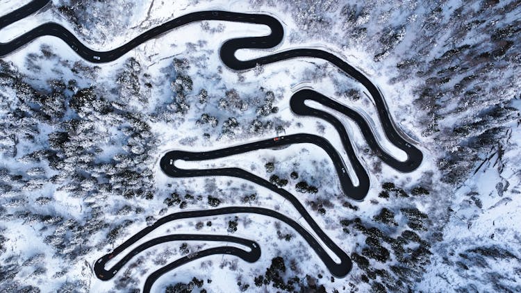 Drone Shot Of A Curvy Road Through A Forest In Winter 