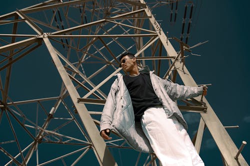 Man Wearing a Gray Jacket Hanging on a Transmission Tower