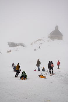 People enjoying sledding on a snowy day with mist and fog enhancing the winter atmosphere.