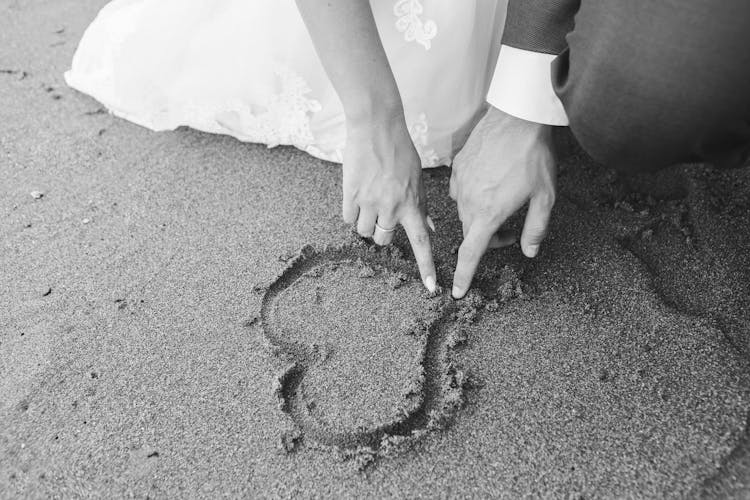 Bride And Groom Drawing A Heart In The Sand 