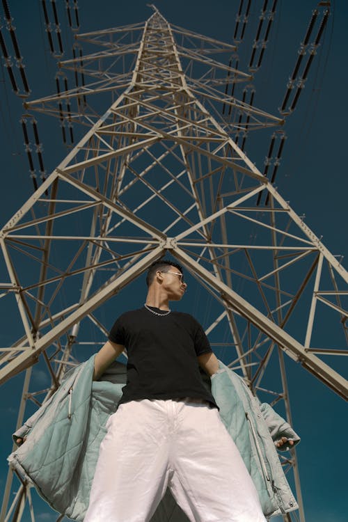 Man in Black Shirt Standing Below an Electrical Post