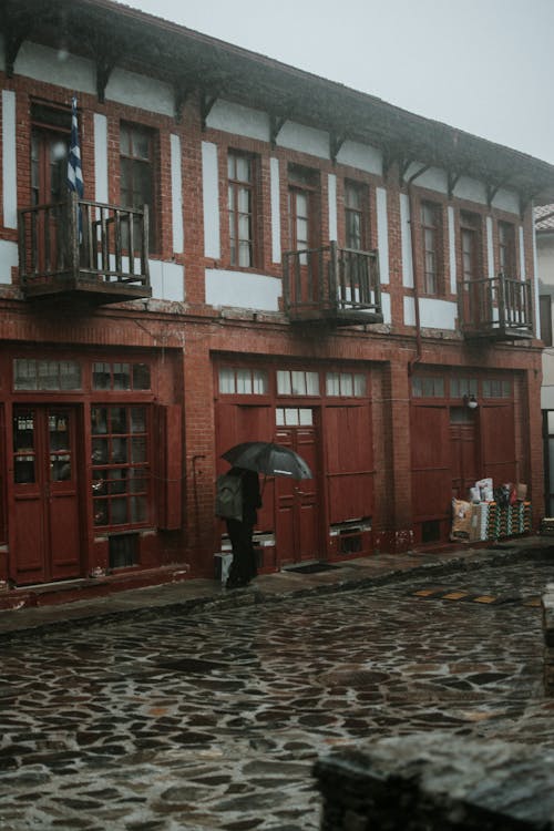 Person with Umbrella Walking by Street in Rain