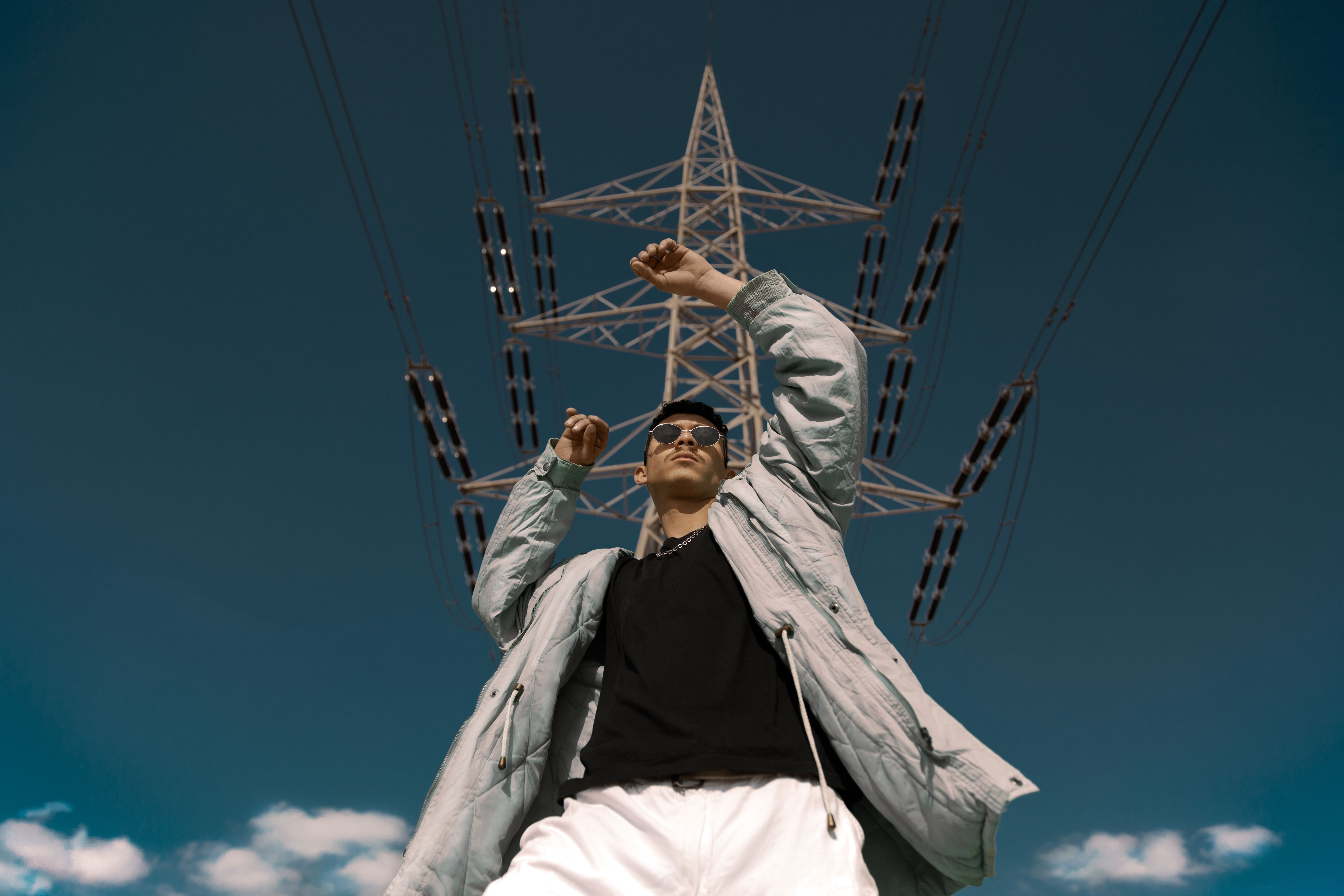 A man standing in front of a high voltage tower · Free Stock Photo