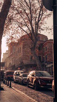 A city street during a traffic jam, lined with historic buildings and autumn trees.