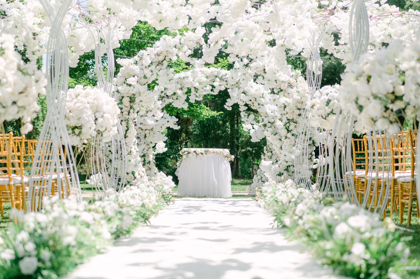 Garden wedding venue with white floral arches and elegant chairs